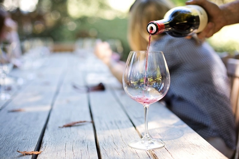 Wine being poured into a glass on an outdoor table